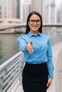 Business, gesture and education concept. Young friendly young smiling businesswoman with opened hand ready for handshake outdoors
