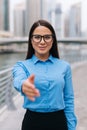 Business, gesture and education concept. Young friendly young smiling businesswoman with opened hand ready for handshake outdoors