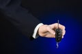 Business and gift theme: car salesman in a black suit holds the keys to a new car on a dark blue background in studio Royalty Free Stock Photo