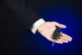 Business and gift theme: car salesman in a black suit holds the keys to a new car on a dark blue background in studio Royalty Free Stock Photo