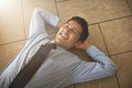 Business is good. High angle shot of a businessman lying on his office floor.