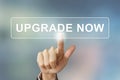 Business hand clicking upgrade now button on blurred background Royalty Free Stock Photo