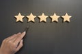 Business hand select five star rating on wooden.