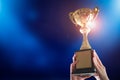 Business hands holding trophy cup on blue background. Selective focus Royalty Free Stock Photo
