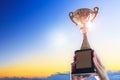 Business hands holding trophy cup on sky background. Royalty Free Stock Photo
