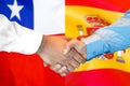 Handshake on Chile and Spain flag background
