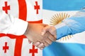 Handshake on Georgia and Argentina flag background