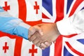 Handshake on Georgia and UK flag background