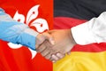 Handshake on Hong Kong and Germany flag background Royalty Free Stock Photo