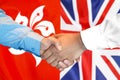 Handshake on Hong Kong and UK flag background Royalty Free Stock Photo