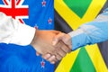 Handshake on New Zealand and Jamaica flag background