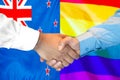 Handshake on New Zealand and LGBT gay flag background