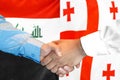 Handshake on Iraq and Georgia flag background. Men handshake on the background of the Iraq and Georgia flag. Support concept