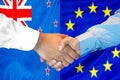 Handshake on New Zealand and European Union flag background