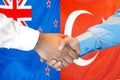 Handshake on New Zealand and Turkey flag background