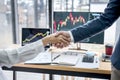 Business handshake after discussion and analyzing graph stock market trading good deal of Trading to sign agreement and become a