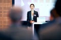 Business, happy woman at podium and presentation with projector screen, conference or workshop with laptop for PPT