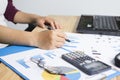 Business holding a pointing pen and calculators on wood