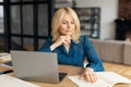 Business from home. Mature woman entrepreneur working with laptop and documents in living room interior Royalty Free Stock Photo
