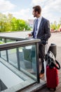 Business, hot drinks and people and concept - young serious businessman with paper coffee cup over office building. Royalty Free Stock Photo