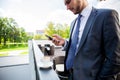 Business, hot drinks and people and concept - young serious businessman with paper coffee cup over office building. Royalty Free Stock Photo