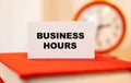 BUSINESS HOURS on a business card against the background of time
