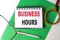 BUSINESS HOURS text on notebook on green paper