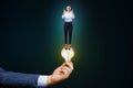 Business idea, startup and success concept with woman on glowing light bulb in man hand on abstract dark background Royalty Free Stock Photo