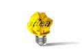 Yellow crumpled paper ball light bulb standing on white floor. Royalty Free Stock Photo