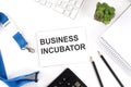 BUSINESS INCUBATOR Words on the card with keyboard and office tools