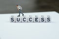 Business, job or career development success concept, miniature figure confident office businessman walking on white cube blocks