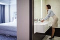 Pretty female in formal wear looking at mirror while washing hands in bathroom Royalty Free Stock Photo