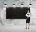 Business lady is holding a black document case. Blank blackboard on the background. Royalty Free Stock Photo