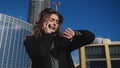 Business lady sets up meeting over the phone looking at clocks amid high-rises