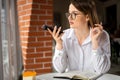 business lady sitting in a cafe dictates a message audio voice recognition on a smartphone, virtual voice assistant Royalty Free Stock Photo