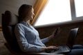 Business lady working from home during the quarantine. Remote work from home. Easy chair, phone and laptop for work.