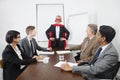 Business leader as superhero in front of colleagues at meeting in conference room Royalty Free Stock Photo