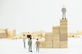 Business leader concept. Miniature people small figure standing in the wood block stacking. With copy space. Teamwork,