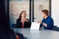 A business leader in a suit conversing with her worker in the IT industry about new business projects and existing