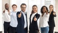 Business leaders with employees showing thumbs up looking at camera