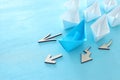 Business. Leadership concept image with paper boats on blue wooden background. One leader guiding othes