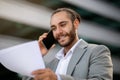 Business Lifestyle. Confident young businessman talking on cellphone and looking at documents Royalty Free Stock Photo