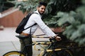 Business, lifestyle, transport and people concept - young asian man parking bicycle on city street