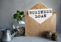 BUSINESS LOAN text is written on white paper on an antique envelope, which lies on the table along with a stack of coins, a glass Royalty Free Stock Photo