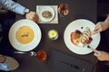 Business lunch or dinner in a restaurant. hands on table, dishes like soup and meat, eating. top view Royalty Free Stock Photo