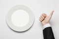 Business lunch and healthy food theme: man's hand in a black suit holding a white empty plate and shows finger gesture on an Royalty Free Stock Photo