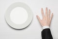 Business lunch and healthy food theme: man's hand in a black suit holding a white empty plate and shows finger gesture on an Royalty Free Stock Photo