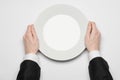 Business lunch and healthy food theme: man's hand in a black suit holding a white empty plate and shows finger gesture on an Royalty Free Stock Photo