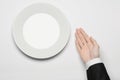 Business lunch and healthy food theme: man's hand in a black suit holding a white empty plate and shows finger gesture on an Royalty Free Stock Photo