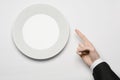 Business lunch and healthy food theme: man's hand in a black suit holding a white empty plate and shows finger gesture on an Royalty Free Stock Photo